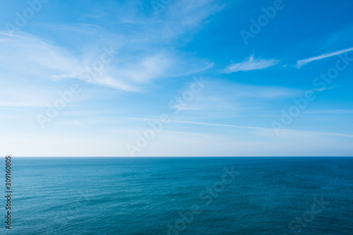 cloudy blue sky leaving for horizon above a blue surface of the sea