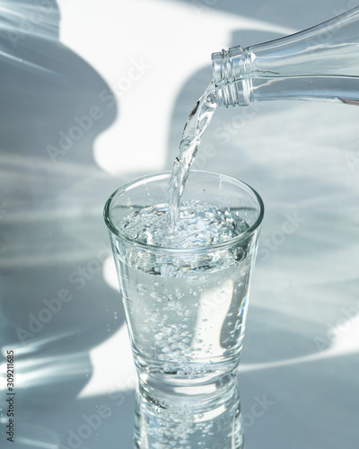 Nalewanie oczyszczonej świeżej wody do picia z butelki na stole w salonie