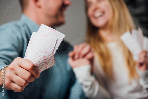 cropped view of happy man and woman holding hands while holding lottery tickets