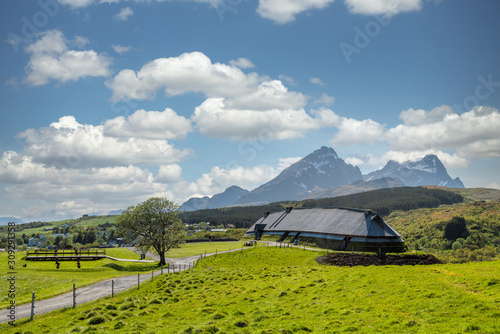 Lofotr long house, a home for vikings in the viking era, during daytime with white clouds. Mountains in the background. Architecture, history and viking concept.