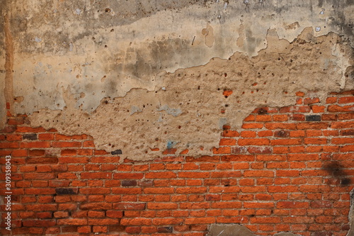 Vintage weathered brick wall with cement plaster finish, part of cement is cracked