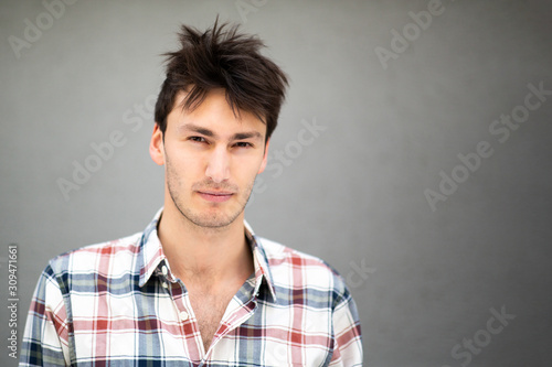 Close up front of serious handsome young man by gray background
