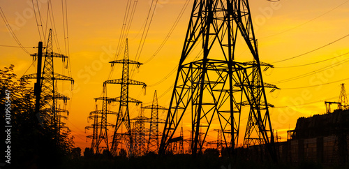Electricity pylons bearing the power supply across a rural landscape during sunset. Selective focus.