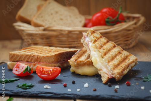 Club or toast sandwiches on black tray. Grilled sandwiches with ham salami, tomato and melted cheese.