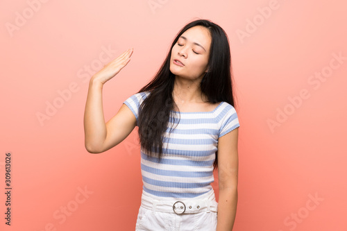 Teenager asian girl over isolated pink background with tired and sick expression