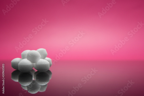 Selective focus of group of mothball isolated in pink background.