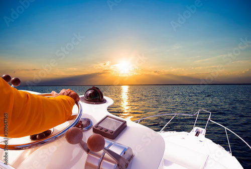 Hand of captain on steering wheel of motor boat in the blue ocean during the fishery day. Success fishing concept. Ocean yacht