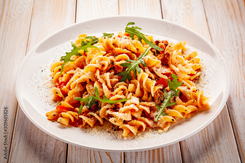 Fusilli with sausages and vegetables on wooden table