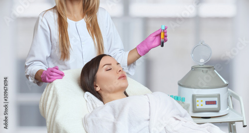 Cosmetologist does prp therapy on the face and scalp of a beautiful, young woman with clean skin in a beauty salon. There is in vitro blood plasma, ready for injection. Cosmetology concept.