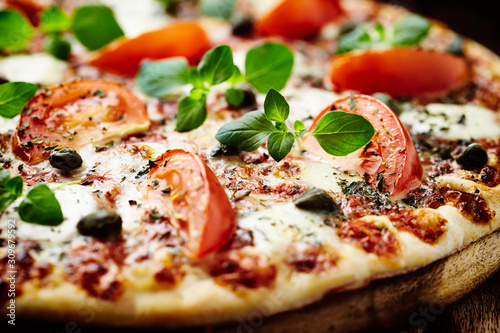 Vegetarian pizza with mozzarella cheese, tomatoes and capers. Close up. 