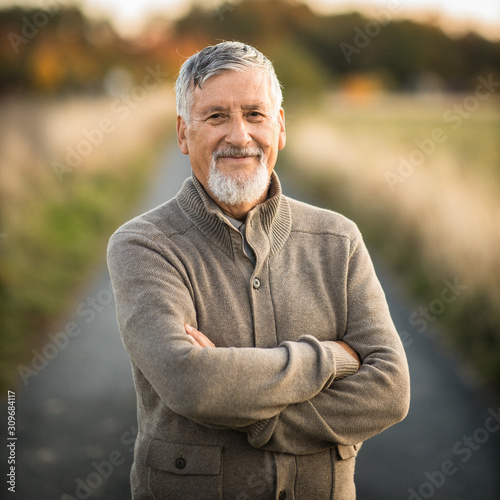 Portrait of handsome senior man in the autumn outdoors. Active senioor enjoying his retirement in the nature