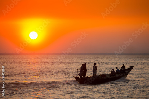 Colorful golden Sunset on Sea. Fishermans are returning home with fish, manually at sunset on Char Samarj beach at Chandpur, Bangladesh.