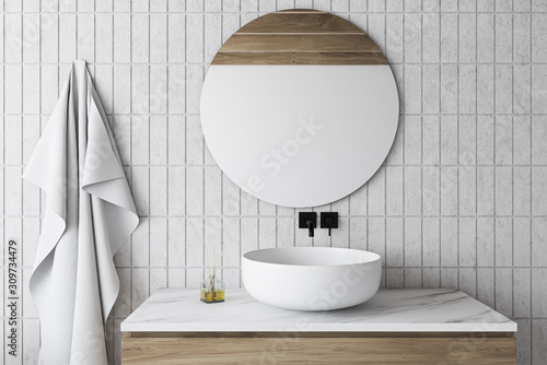 White tile bathroom with sink and round mirror