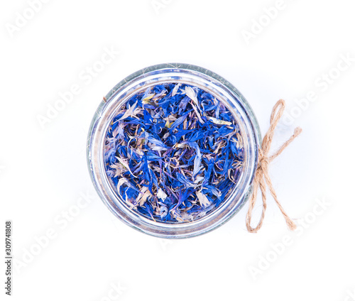 Blue cornflower centaurea dried petals in a glass jar isolated on white background.