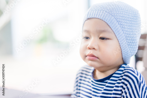 Little asian toddler boy wear hat and yawning in winter time.2 years old boy make sleepy face and tired face.