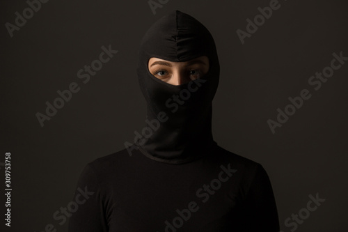 Unknown woman in a black mask on a gray background