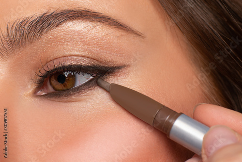 Beautiful eye of woman with amazing make up. Girl is applying eyeliner on eyes