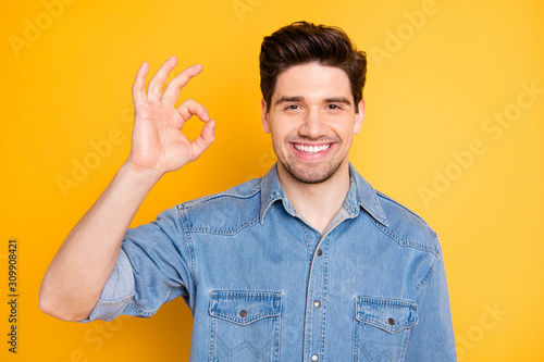 Portrait of positive cheerful guy promoter show okay sign advise promo ads wear casual style clothing isolated over yellow color background