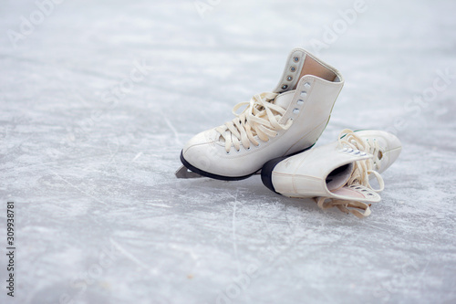 A pair of White Figure Skates lie on an open ice rink