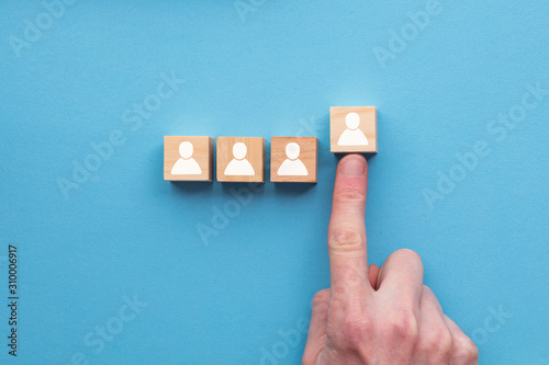 Hand choosing a wooden person block from a set. Employment choice concept