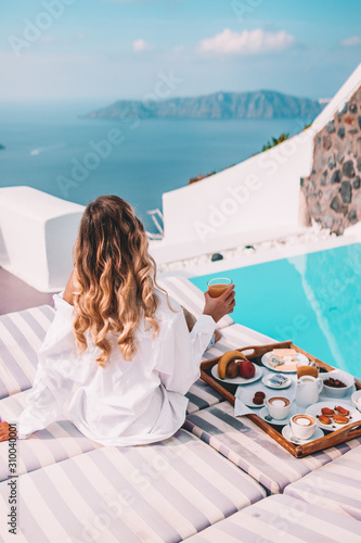 Woman having breakfast by the pool in santorini, greece