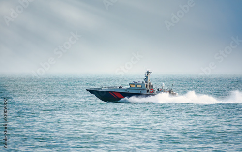 A coast guard patrol boat sails near the shore
