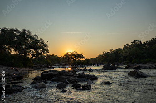 Sunset in Malawi river with trees, rocks and text space