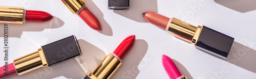 top view of assorted lipsticks in luxury tubes on white background, panoramic shot
