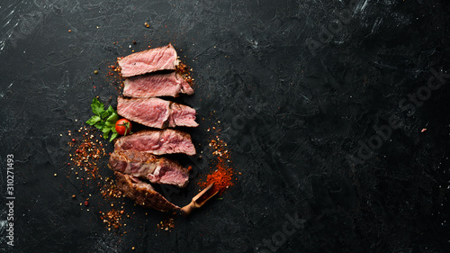 Sliced grilled steak on black stone background. Black Angus. Top view. free space for your text. Rustic style.