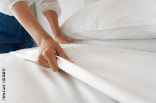 Female Hand set up white bed sheet in bedroom