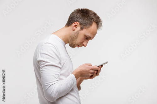 Close up portrait of man looking and using smart phone with scoliosis, side view, isolated on gray background. Rachiocampsis, kyphosis curvature of neck, Incorrect posture, , orthopedics concept