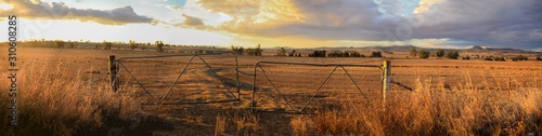 Panoramic views of dry, drought stricken farm land through old steel locked farm gates on a hot afternoon in Gunnedah, New South Wales, rural Australia