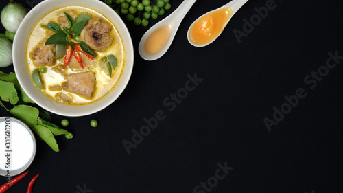 Top view of chicken green curry and ingredients on black desk background, Thai cuisine concept