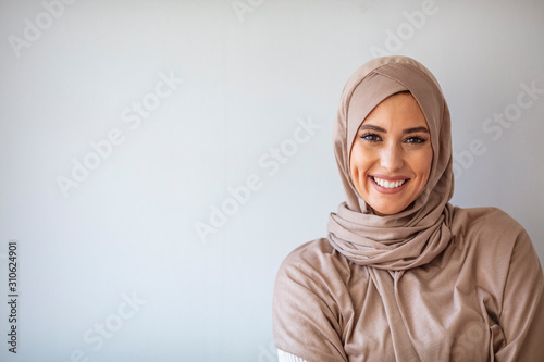 Portrait of pretty young asian muslim woman in head scarf smile. Portrait closeup of muslim prayer woman 20s in hijab smiling isolated over gray background.