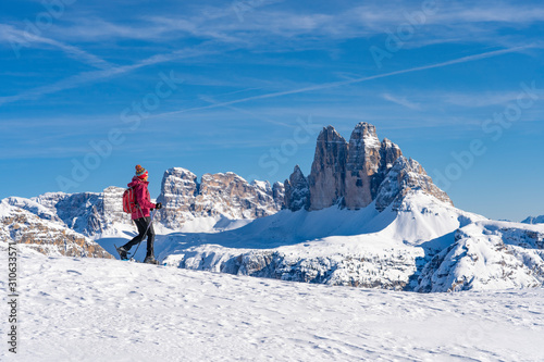 active senior woman snowshoeing under the famous Three Peaks, Dolomites near village of Toblach, South Tyrol, Italy