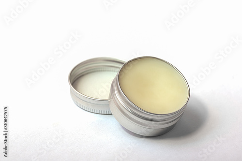 Lip balm in the round metallic tins on the white background