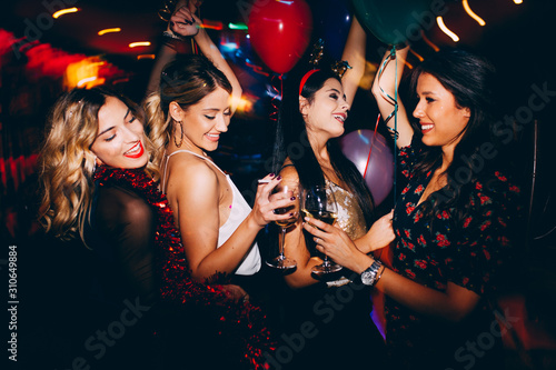 Female friends drinking wine and celebrating new year at the club