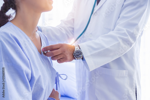 Doctor use stethoscope, checking up heart beat, lunch of auscultation in doctor office at hospital. Patient worker has to get medical checkup every year for her health or medical checkup cardiologist