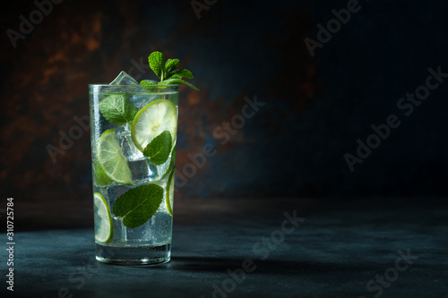 Mojito cocktail on black background with lime and mint with copy space