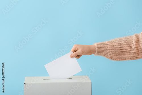 Voting woman near ballot box on color background