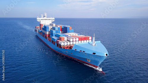 Large container ship at sea, loaded with various container brands. ULCV container ship sails on open water fully loaded with containers and cargo.