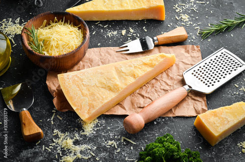 Piece of Parmesan cheese and cheese knife. On a stone background. Traditional Italian cheese. Top view. Free space for your text.