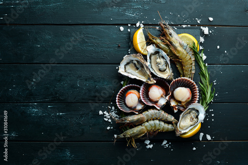 Seafood. Oysters, scallops, shrimp. Top view. On a black background. Free copy space.
