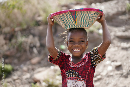 Body Shot of Cute African Young Girl Carrying Food Basket and Blurred Background