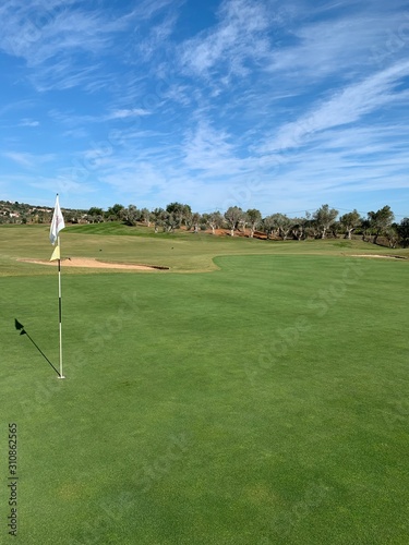 golf green with blue sky and bunkers