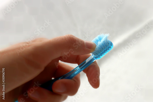 Used old toothbrush with a frayed bristles in hand on light background