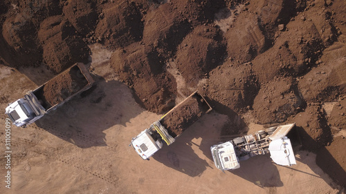 Dump truck unloading soil on a new construction site. Top view on Truck loaded with Soil.