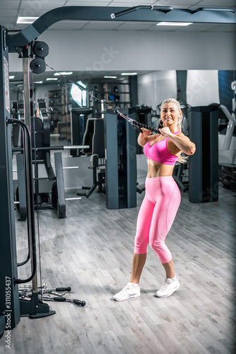 Blonde woman doing rope pushdown triceps exercise.