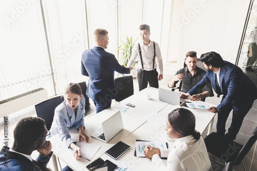 A team of young businessmen working and communicating together in an office. Corporate businessteam and manager in a meeting