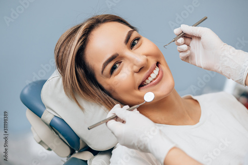 portrait of young caucasian woman with perfect smile in dental office, come to treat spoiled teeth, look at camera